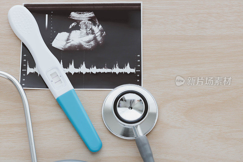 妊娠检查显示阳性结果和听诊器，超声图像婴儿孤立在木制背景。超声检查结果，孕期超声检查结果。孕期保健的概念。