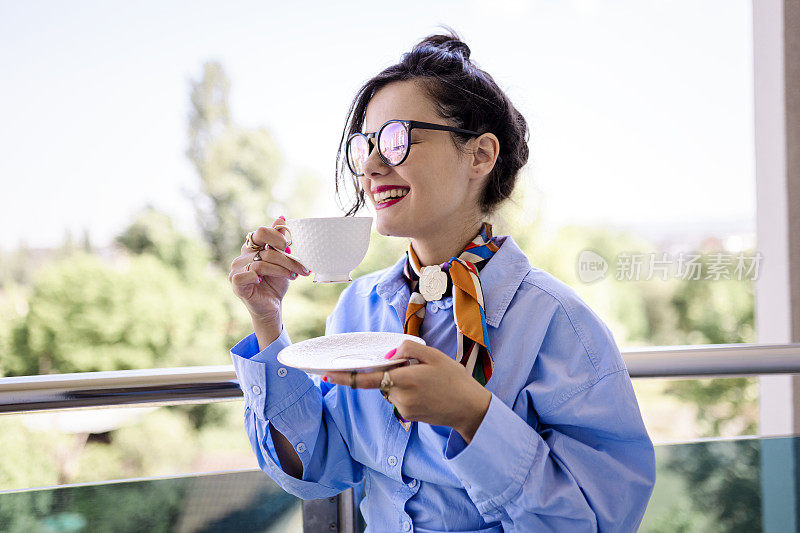 快乐的女人在阳台上喝咖啡