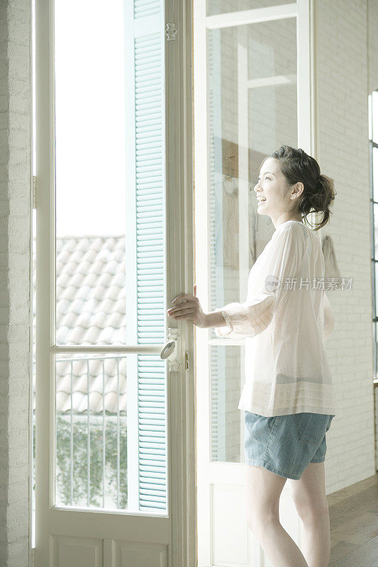 一个年轻的女人从开着的窗户往外看