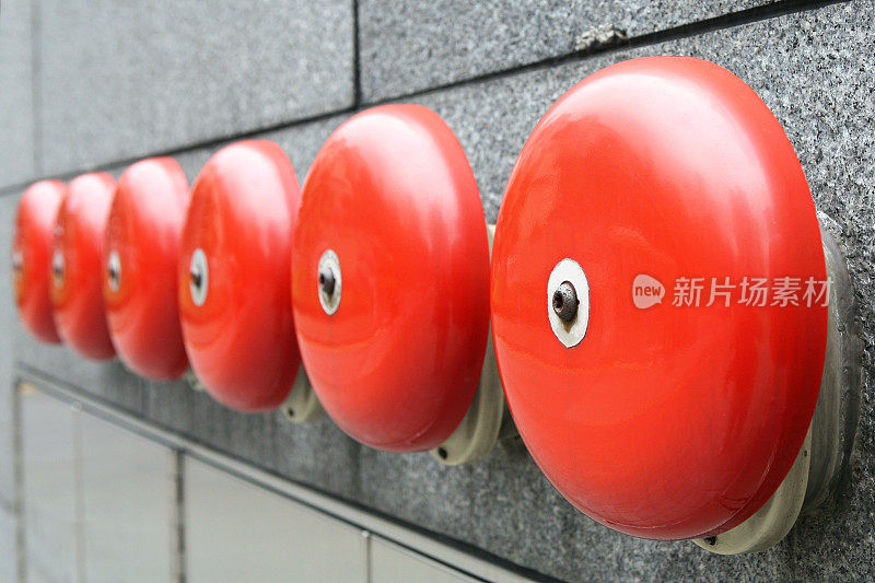 六个红色警铃排列在一堵砖墙上