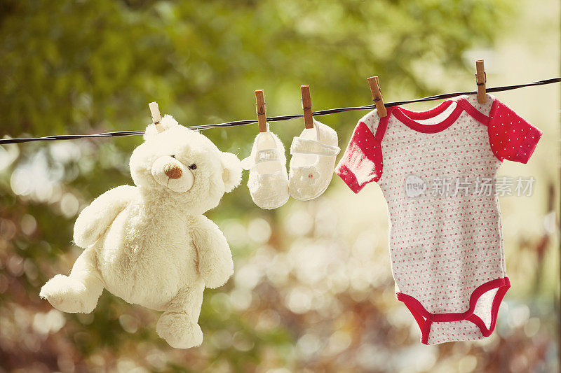 晾衣绳上挂着婴儿衣服和泰迪熊