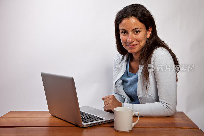 年轻女子拿着笔记本电脑对着镜头微笑