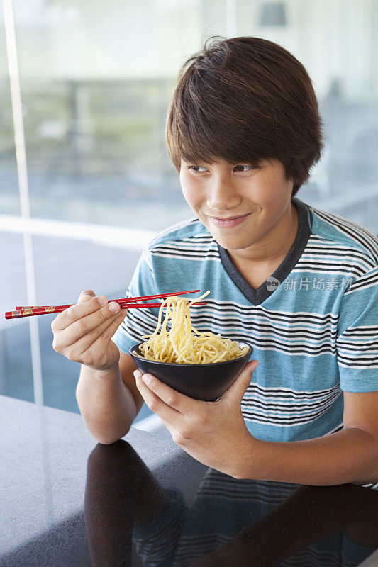亚洲男孩在吃一碗面条