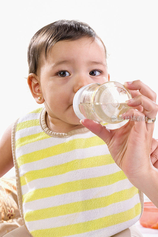 小女孩戴着围嘴，用奶瓶喝水