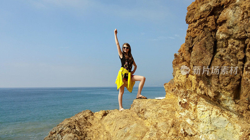 女孩站立，岩石悬崖，胜利手臂，马里布，加利福尼亚