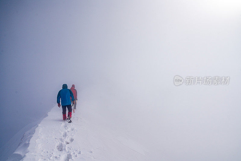 两个人走在雪山的山峰上进入云中