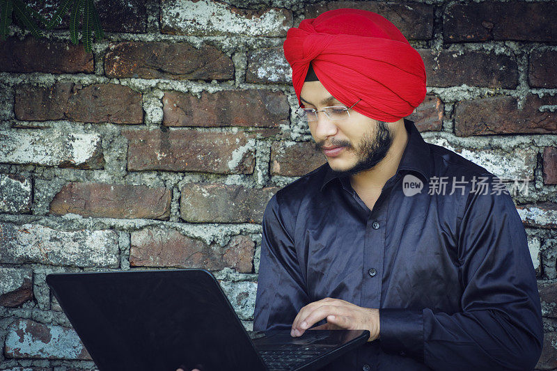 年轻的锡克教徒拿着电脑在城市做生意