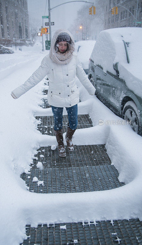 少女走在曼哈顿的街道上的雪下