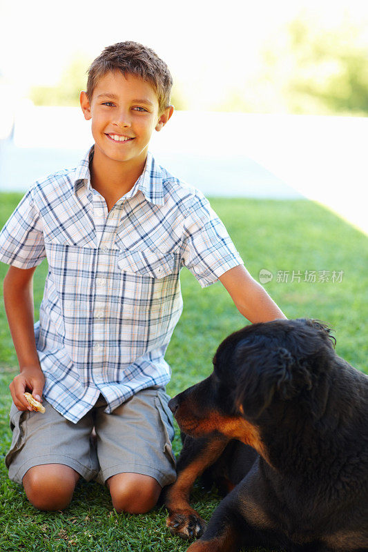 一个小男孩和他的宠物狗坐在户外