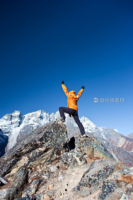 喜马拉雅山脉，一位女性登山者举起她的手臂表示胜利