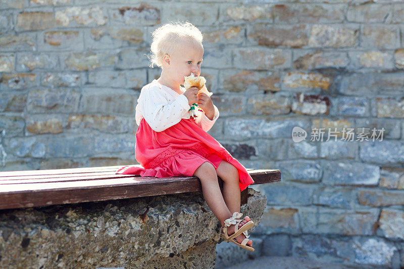 小女孩在长凳上吃面包