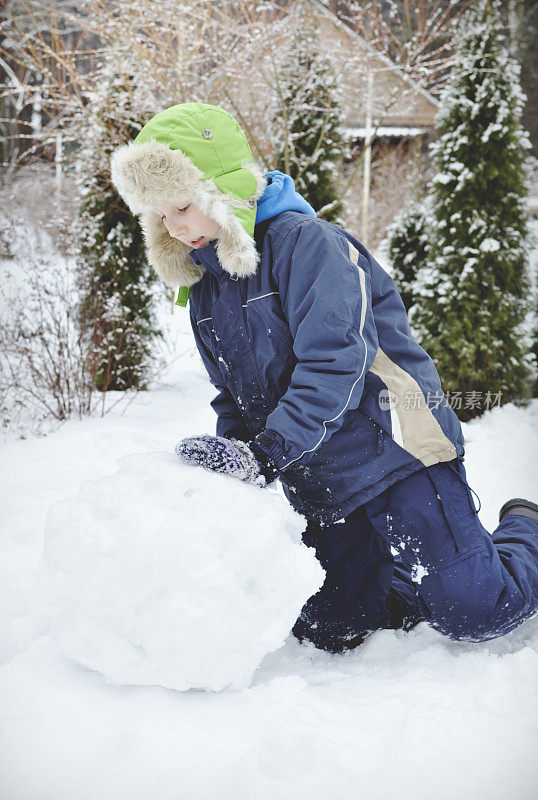 快乐的男孩在冬天堆雪人