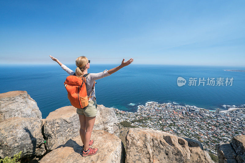 开普敦的一位年轻女子站在山顶，双臂张开