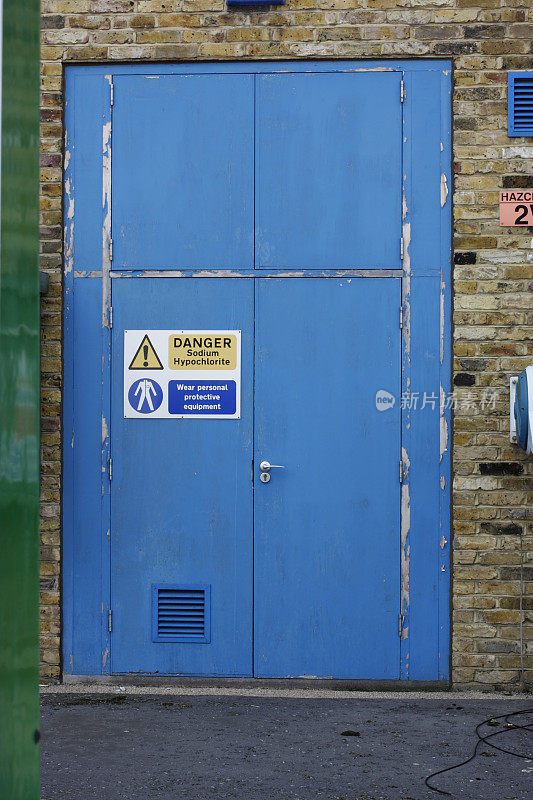 蓝色门上的次氯酸钠危险化学物质警告标志