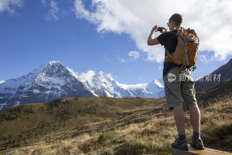 一个徒步旅行者用智能手机拍下了山的照片