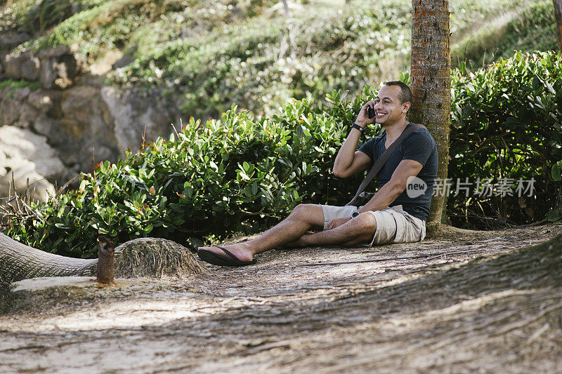 一个在海滩上玩智能手机的快乐男人