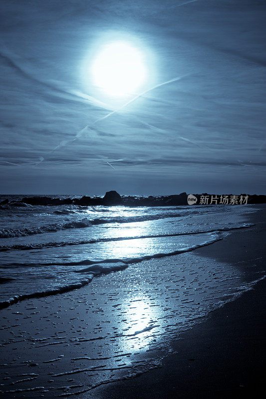 月光下的海洋在海滩岸边的波浪上反射