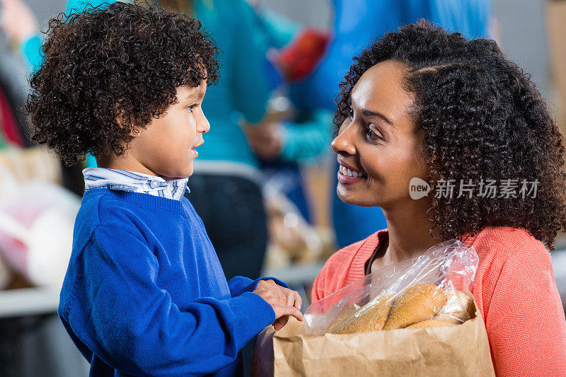 妈妈和小儿子在食品银行捐赠食品