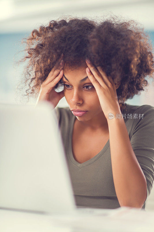 忧心忡忡的非洲裔美国妇女使用笔记本电脑。