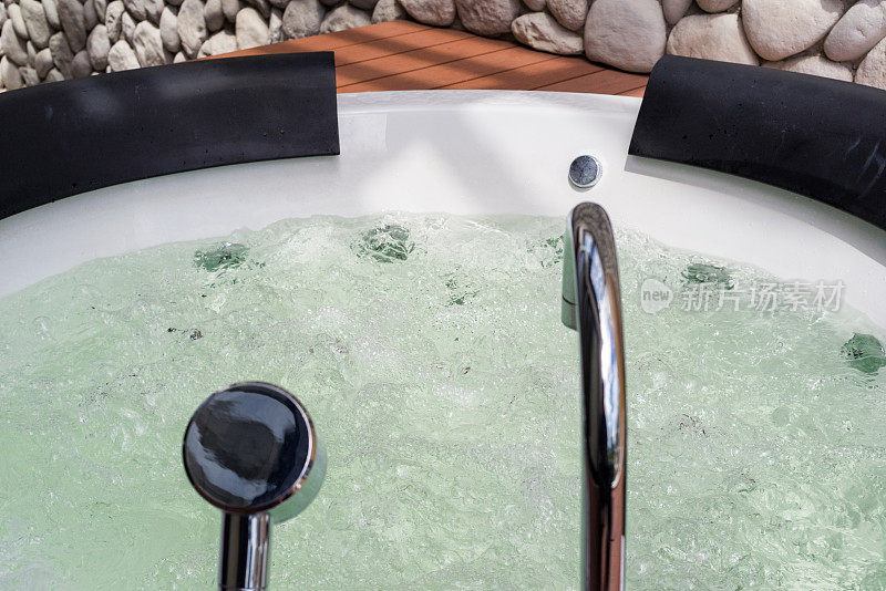 白色漩涡浴缸与水气泡和钢水龙头