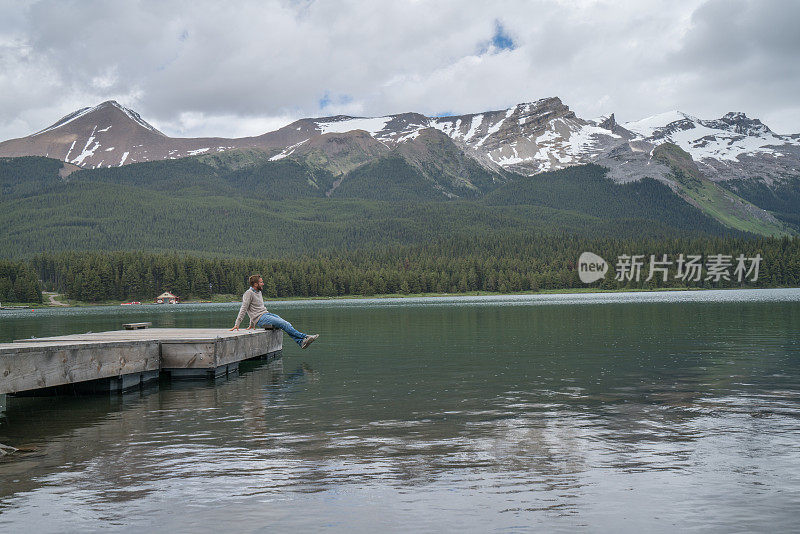 年轻人在湖边码头上看山景