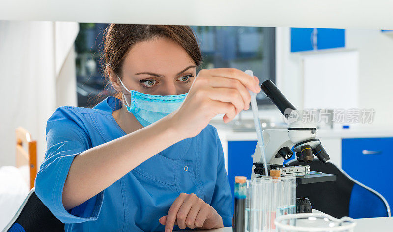 在实验室里，穿着制服的年轻女科学家用移液管从试管中抽取液体进行研究