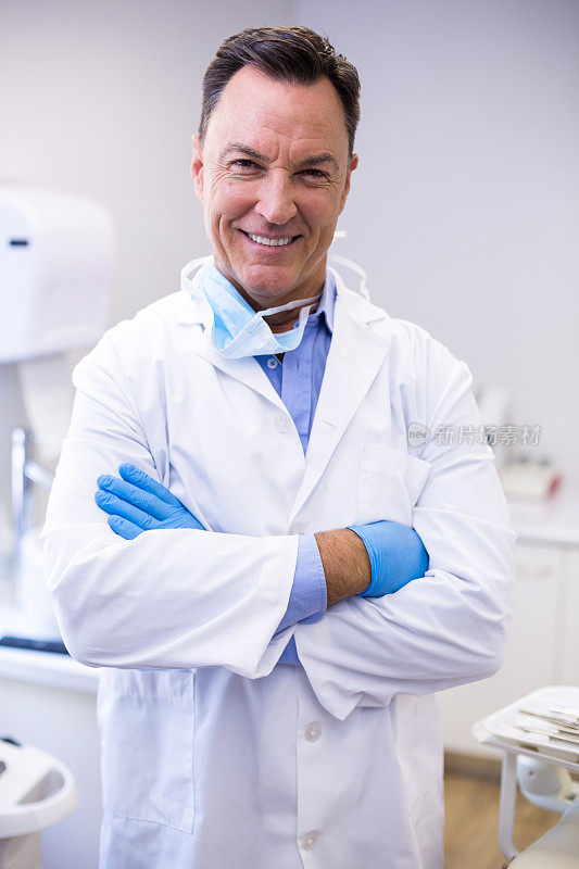 牙科医生双臂交叉微笑站在牙科诊所