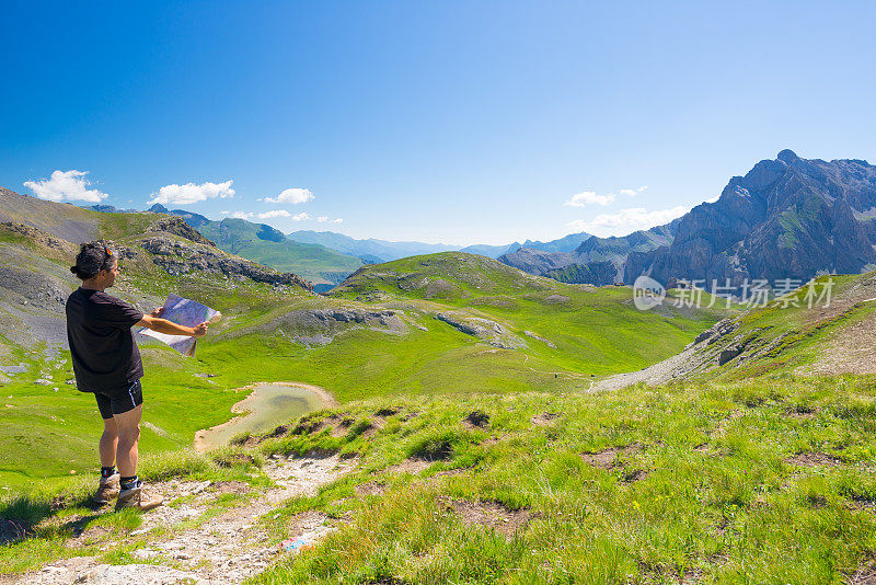 徒步者一边阅读徒步地图，一边在全景景点休息。户外活动，夏季冒险和探索在意大利的法国阿尔卑斯山。从顶部开阔的视野。