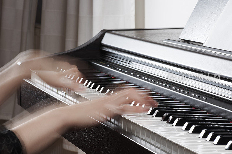 木质的黑色钢琴与键盘和女性音乐家的手模糊的运动，与模糊的背景