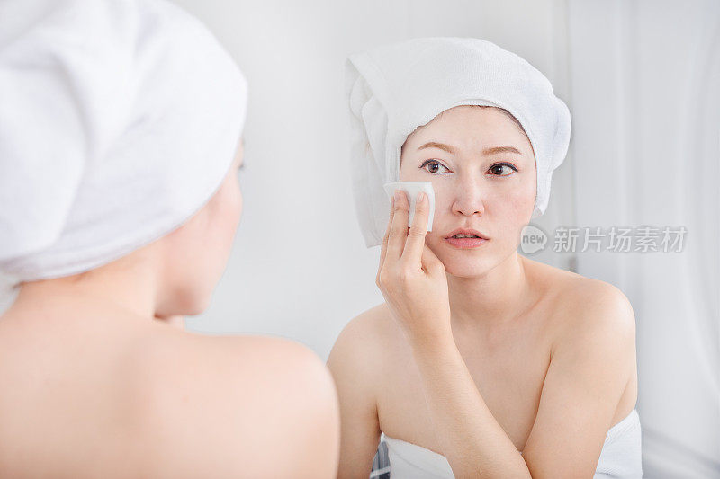 女人照镜子，用棉花擦脸
