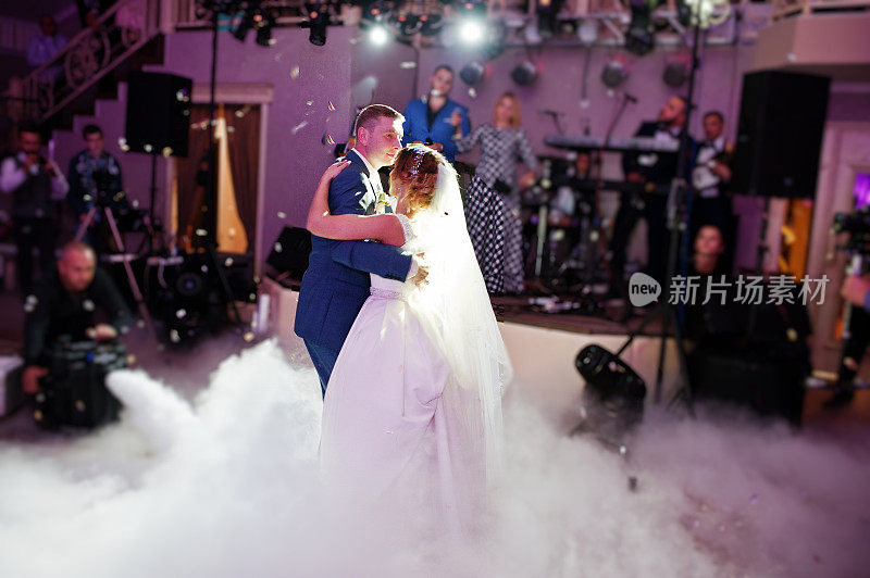 新婚夫妇在他们的婚礼上以浓重的烟雾和彩灯为背景跳舞。