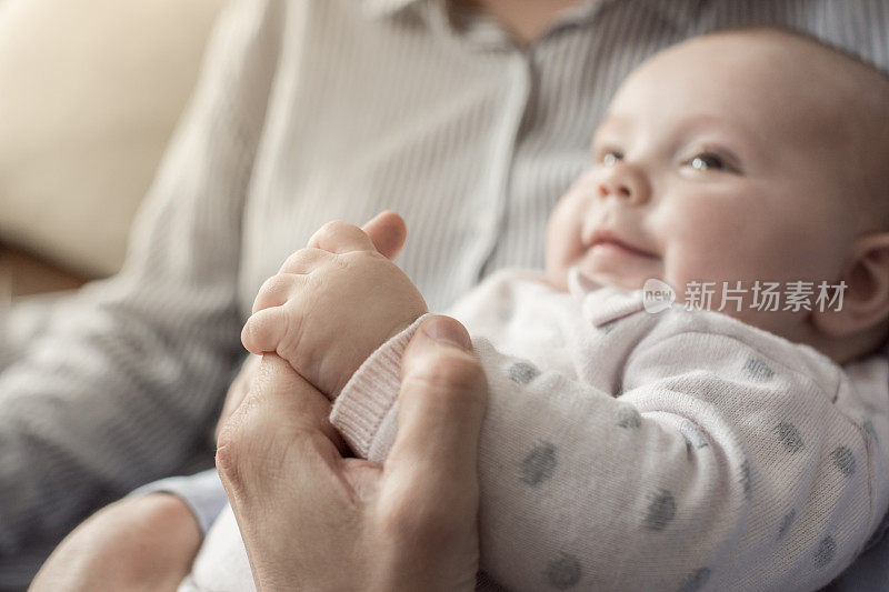 婴儿在母亲的膝上，握着她的手指