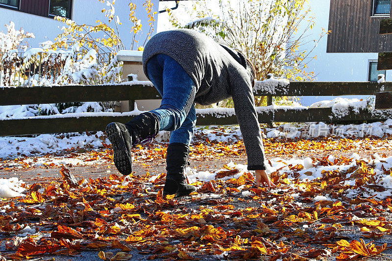 秋冬有滑落的风险。一个女人滑倒在潮湿光滑的树叶上