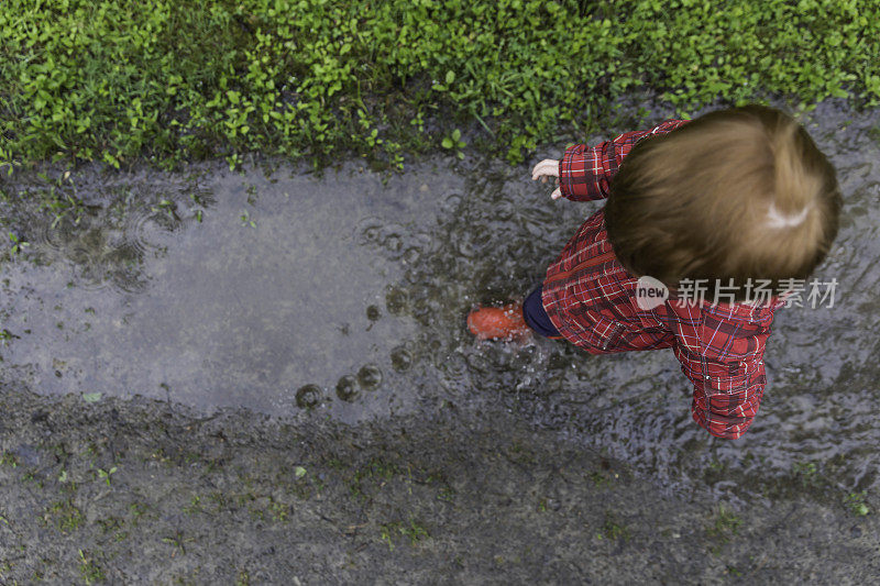 年轻可爱的孩子走着跳进水坑里