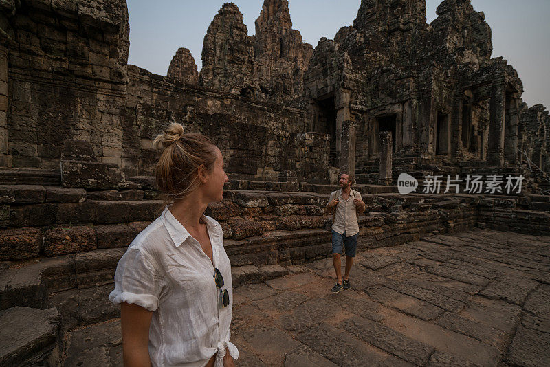 一对在亚洲旅游的游客，在夕阳下凝视美丽的古庙和古老的废墟;人发现探索理念