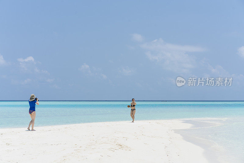 4月，美丽的女人在水边散步，在小岛屿的海滩上拍照