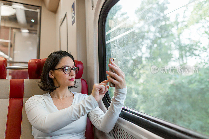 一名女子在火车内使用科技拍照