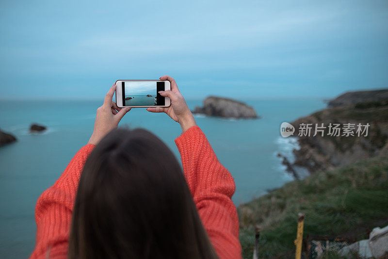 一个年轻的女人在拍一张大海的照片