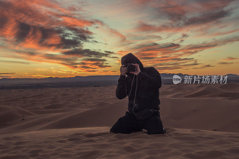 一名男子摄影师正在拍摄撒哈拉沙漠日落