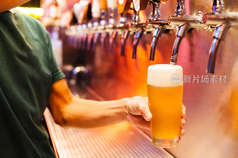 从啤酒龙头倒精酿啤酒在冰冻的玻璃泡沫。有选择性的重点。酒精的概念。复古风格。啤酒工艺。酒吧表。钢铁龙头。闪亮的水龙头。