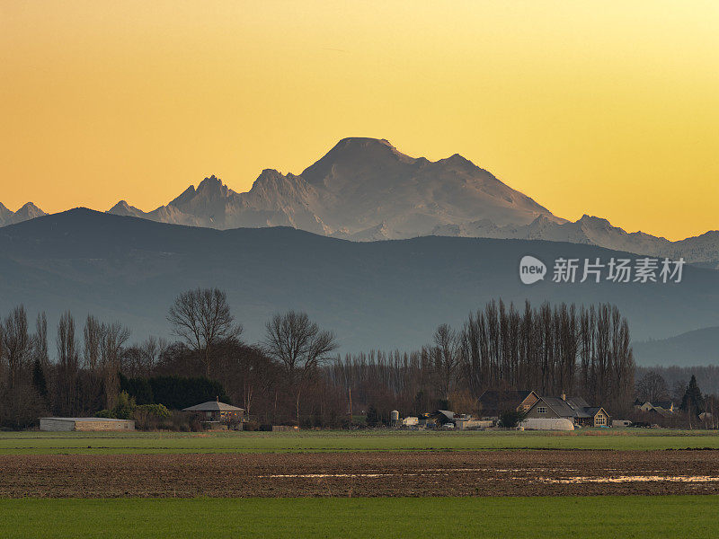 日落时分，风景如画的农田和雪山