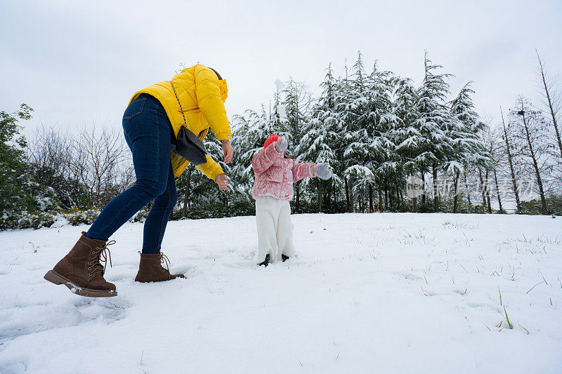 一个小女孩和妈妈在雪中玩耍