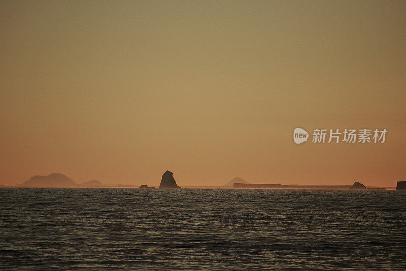 南极泻湖上的日落与漂流的冰山和雪峰的背景，勒梅尔海峡，南极洲