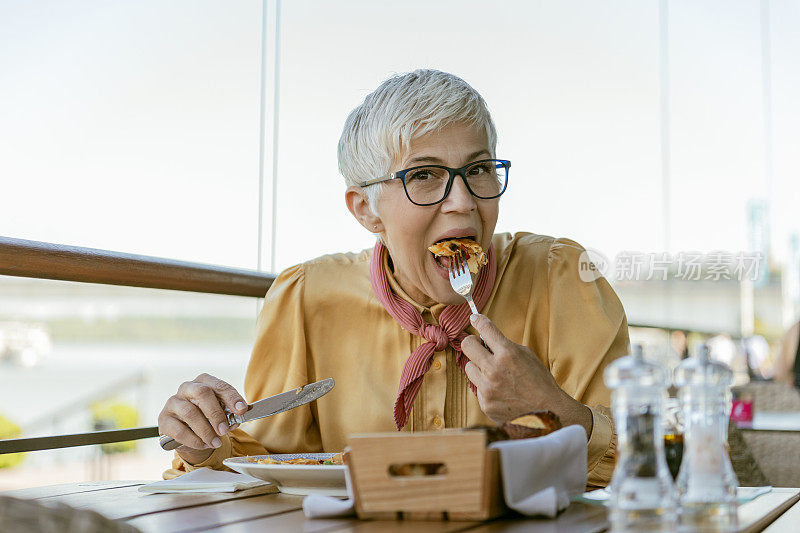 快乐的年长妇女享受在她的午餐在餐厅。