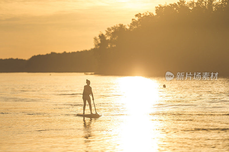 日落时分，女性站起来在河上划桨