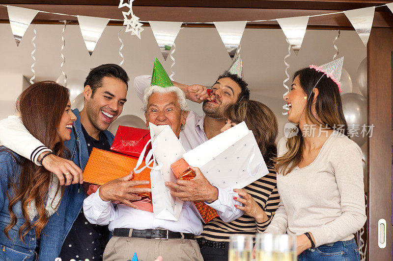 拉丁家庭一起庆祝爷爷的生日。他戴着许多礼物，脸上带着快乐的表情