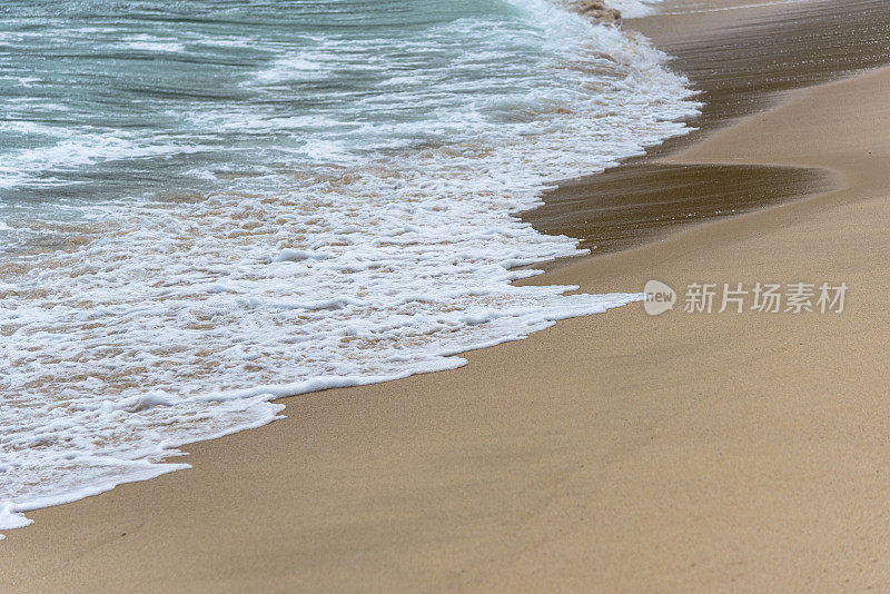 小波浪浸湿了海滩上的沙子