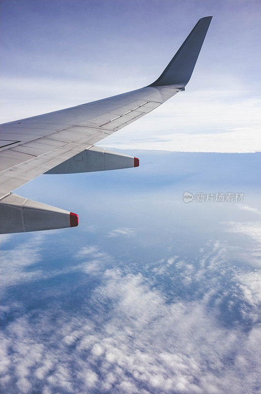 透过窗户看到的飞机机翼，在云层之上飞行