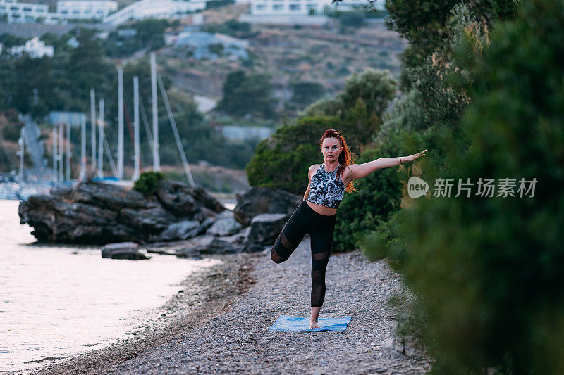 日落时分，年轻女子在海滩上做瑜伽