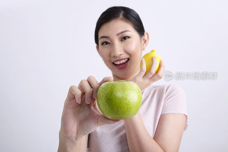 特写的中国民族妇女比较苹果和柠檬